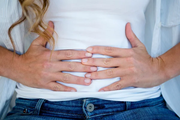 Mujer agarrando su estómago en la incomodidad —  Fotos de Stock