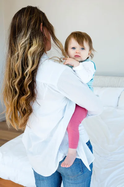 Mulher segurando um bebê adorável em um quarto — Fotografia de Stock