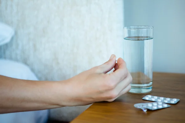 Bricka med piller bredvid ett glas vatten — Stockfoto