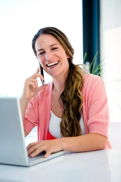 Femme souriante sur son ordinateur portable et téléphone mobile — Photo