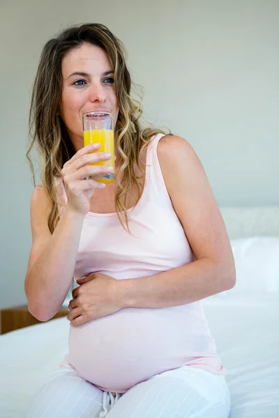 Tired pregnant woman drinking orange juice — Stock Photo, Image