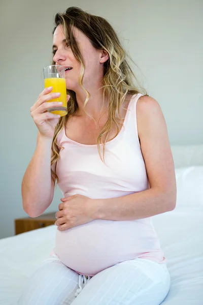 Mulher grávida cansada beber suco de laranja — Fotografia de Stock