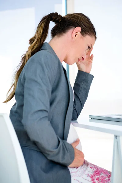 Беременная деловая женщина с головной болью — стоковое фото