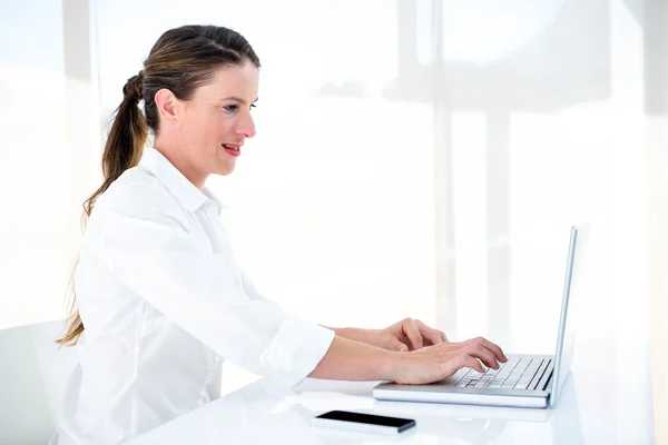 Sonriente mujer de negocios escribiendo en su portátil — Foto de Stock