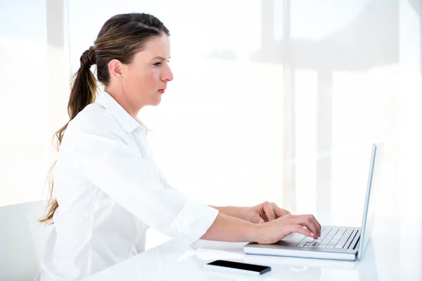 Mujer de negocios grave escribiendo en su computadora portátil —  Fotos de Stock