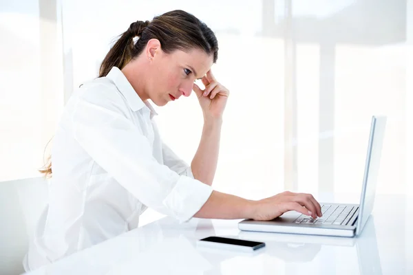Mujer de negocios grave escribiendo en su computadora portátil — Foto de Stock
