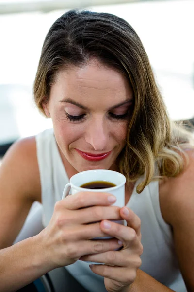 Wanita tersenyum menghirup secangkir kopi — Stok Foto