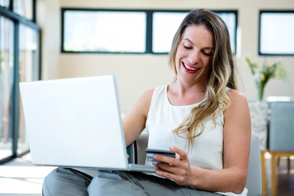 Mujer sonriente en su computadora portátil con tarjeta de crédito — Foto de Stock