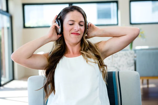 Mulher sorrindo ouvindo fone de ouvido — Fotografia de Stock