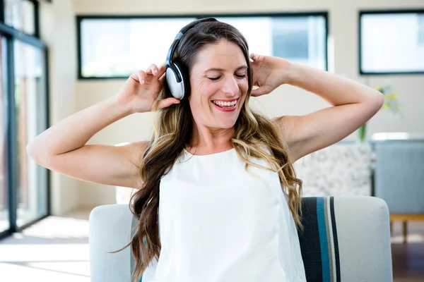 Mujer sonriente escuchando música en sus auriculares — Foto de Stock