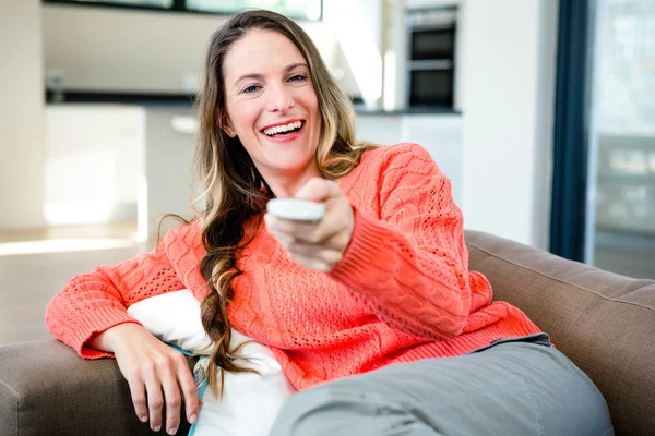 Woman holding a remote control and smiling — Stock Photo, Image