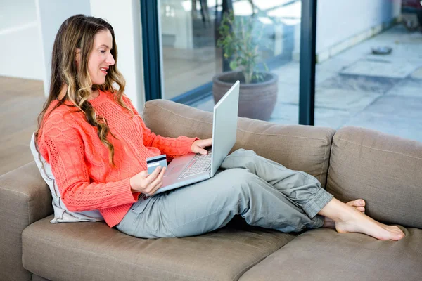 Mulher sorridente em seu laptop com seu cartão de crédito — Fotografia de Stock