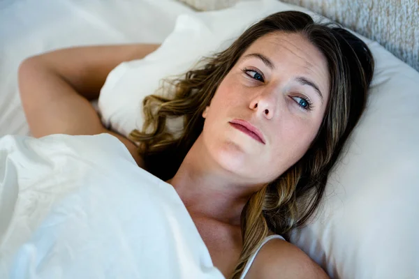 Mujer acostada en la cama mirando al espacio — Foto de Stock