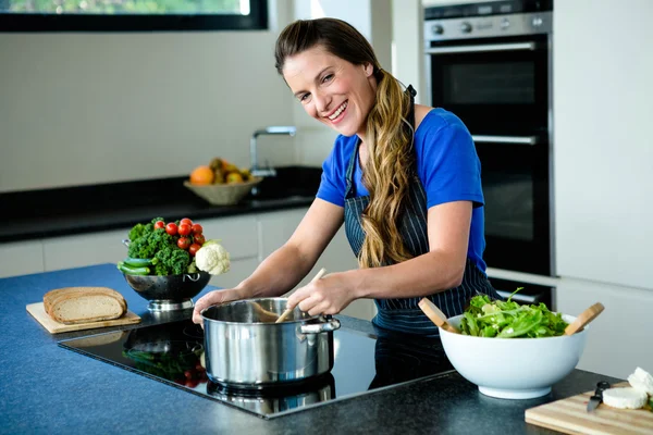 Lachende vrouw koken op het fornuis top — Stockfoto