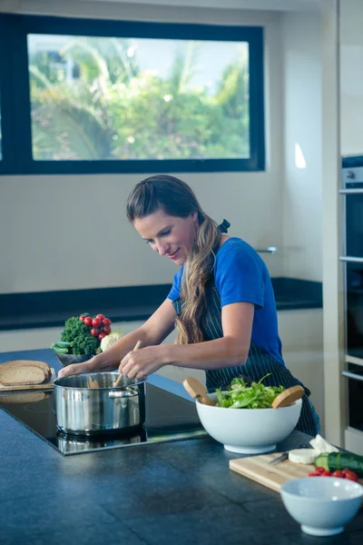 Femme souriante cuisine sur la cuisinière — Photo