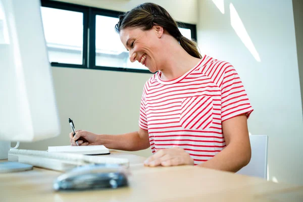 Sorridente mulher de negócios escrevendo em um bloco de notas — Fotografia de Stock