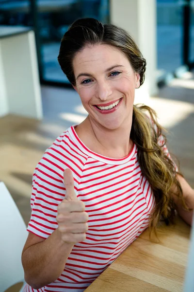 Donna sorridente alla fotocamera dando pollici in su — Foto Stock