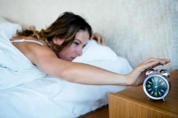 Woman reaching to turn off her alarm clock — Stock Photo, Image