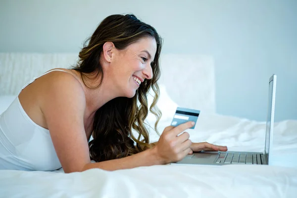 Žena na jejím počítači drží její kreditní karty — Stock fotografie