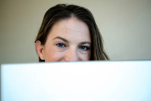 Mulher olhando sobre a parte superior de sua tela de laptop — Fotografia de Stock