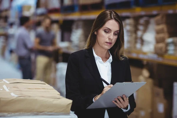 Warehouse manager writing on clipboard — Stock Photo, Image
