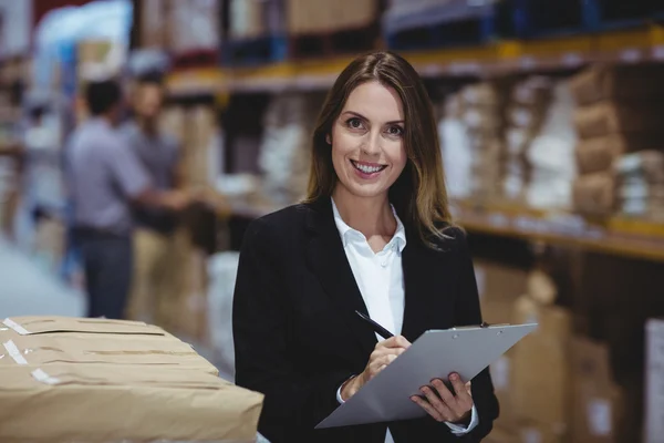 Warehouse manager writing on clipboard — Stock Photo, Image