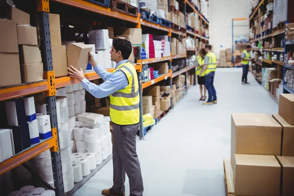 Lächelnder Lagerarbeiter nimmt Paket entgegen — Stockfoto