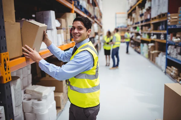 Sorrindo trabalhador armazém levando pacote — Fotografia de Stock