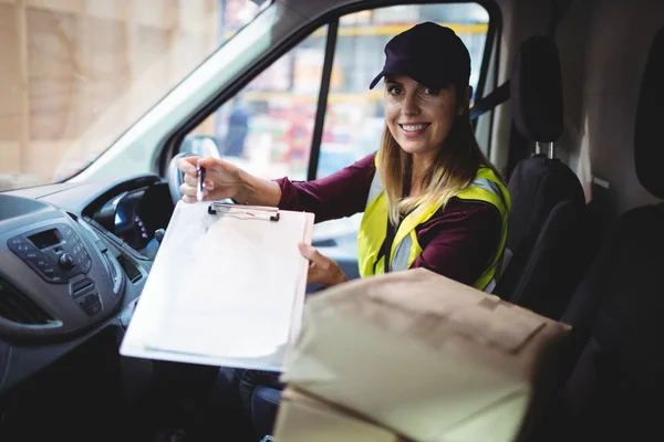 Delivery woman holding clipboard to camera — Stock Photo, Image