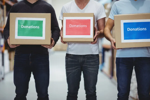 Voluntarios sonriendo a la cámara sosteniendo cajas de donaciones — Foto de Stock