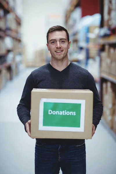 Voluntario sonriendo a la cámara que sostiene la caja de donaciones — Foto de Stock