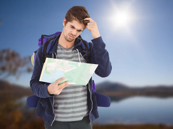 Man scratching head while looking in map — Stock Photo, Image