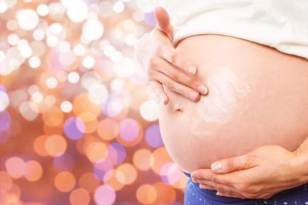 Pregnant woman with cream on bump — Stock Photo, Image