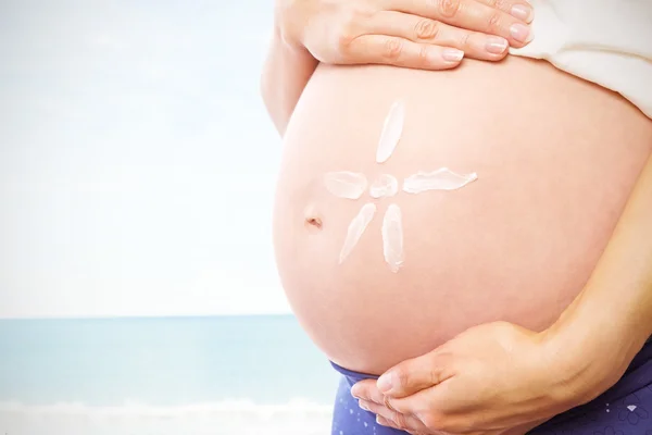 Беременная женщина со сливками на шишке — стоковое фото