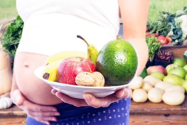 Femme enceinte montrant des fruits — Photo