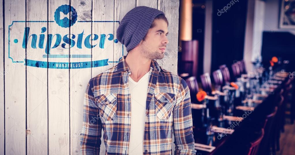 Confident hipster looking away while standing against wooden planks