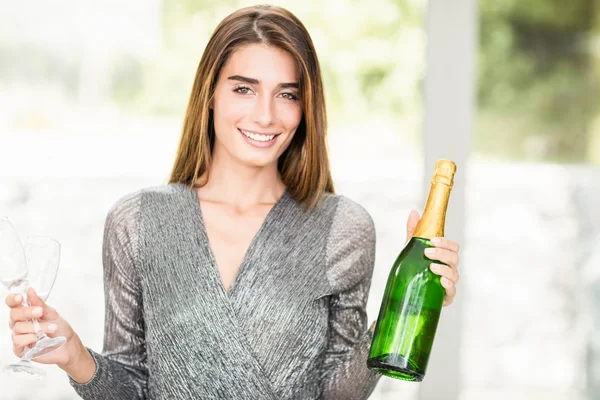 Woman holding champagne bottle and glass — Stock Photo, Image
