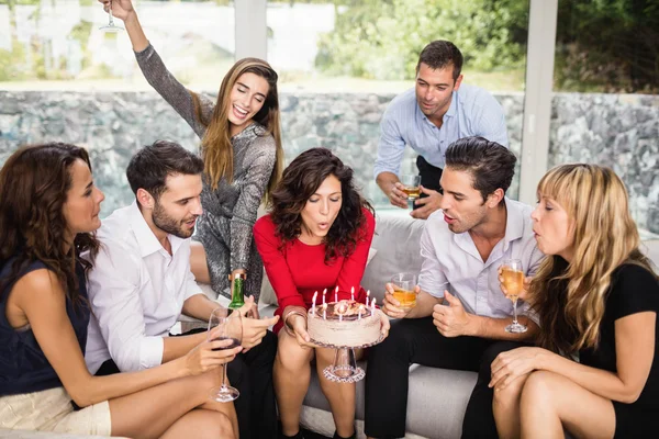 Vrouw waait birthday kaarsen met vrienden — Stockfoto