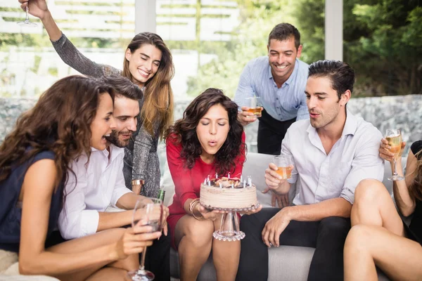 Woman blowing birthday candles with friends — Stock Photo, Image