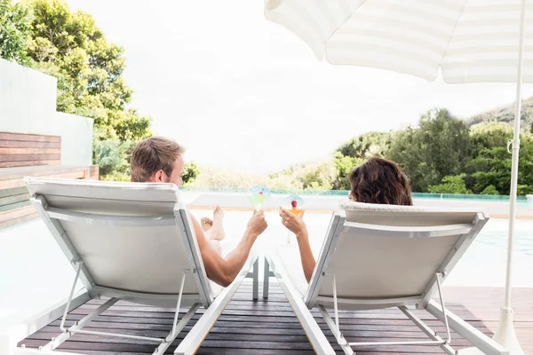 Jeune couple assis sur des chaises longues — Photo