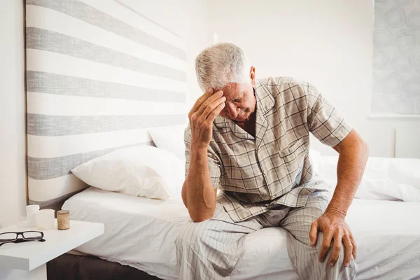 Frustrerad äldre man sitter på sängen — Stockfoto