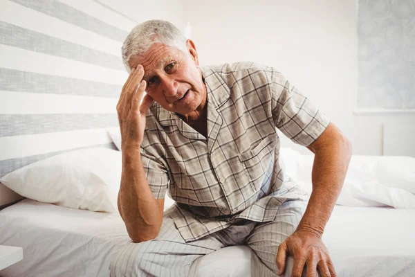 Sfrustrowany starszy mężczyzna siedzi na łóżku — Zdjęcie stockowe