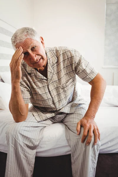 Frustrerad äldre man sitter på sängen — Stockfoto