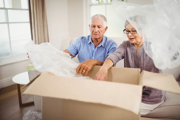 Senior couple unpacking a cardboard box — Stock Photo, Image