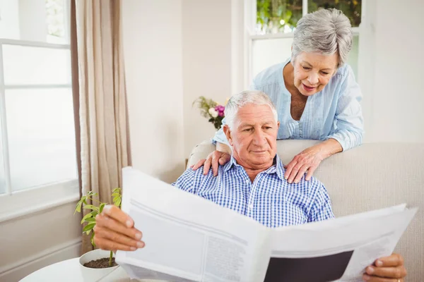 Mujer hablando con el hombre leyendo el periódico — Foto de Stock