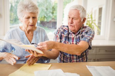 Worried senior couple discussing bills clipart
