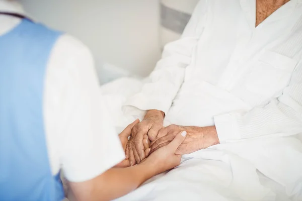 Äldre kvinna och sjuksköterska hand i hand — Stockfoto