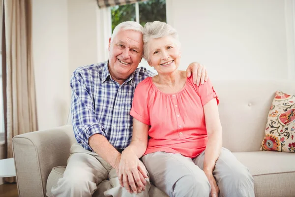 Äldre par sitter på soffan leende — Stockfoto