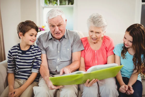 Couple reading book with grand children — Stock Photo, Image