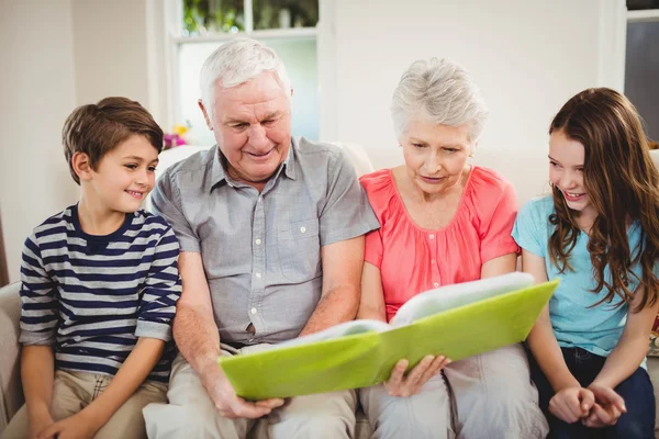 Couple reading book with grand children — Stock Photo, Image